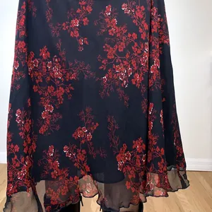 Detailed macro view of an ethnic red floral print on a black chiffon midi skirt