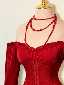 Dettaglio di un elegante abito rosso con spalle scoperte e inserto jacquard fiorito.