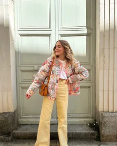 Detailansicht einer bunten, gesteppten Blumenjacke, kombiniert mit einer gelben Hose