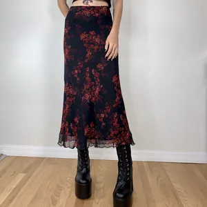 Close-up detail of a vintage black midi skirt featuring elegant red floral print and sheer hem