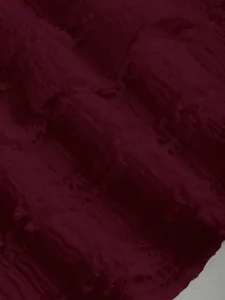 Dettaglio ravvicinato di tessuto bordeaux a balze con elegante trama plissettata e strati