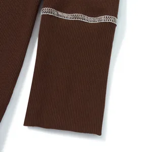 Primo piano di manica di maglione a coste marrone con dettaglio cuciture a contrasto.