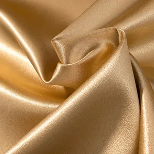 Detailed macro view of luxurious golden satin fabric texture with elegant shimmering finish