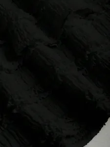 Vista macro del tessuto plissettato nero strutturato per un completo da donna alla moda