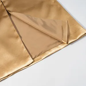 Close-up detail of golden satin skirt hem showing slit design and inner lining texture.