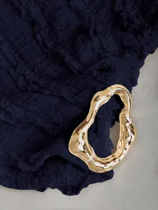 Dettaglio del tessuto strutturato blu navy con fibbia in metallo dorato irregolare