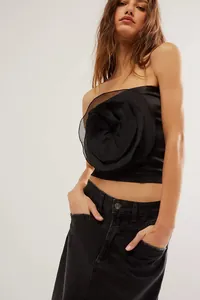 Primo piano di un elegante top a fascia nero con decorazione a fiore in tessuto grande.