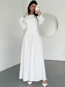 Elegante witte maxi-jurk met boothals, lange mouwen en een getailleerde A-lijn rok