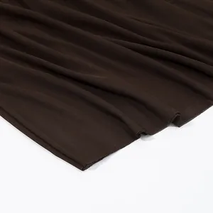 Detailansicht von dunkelbraunem elastischem Netzgewebe mit feiner Textur und Faltenwurf.