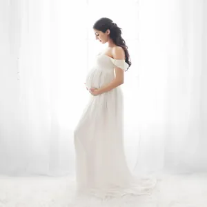 Detailed macro view of elegant white off-shoulder maternity maxi dress for photography session