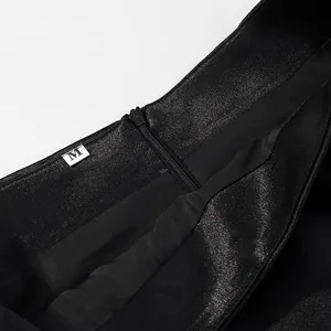 Macro detail of the invisible zipper and size label on black shimmering fabric set.