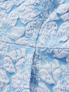 Close-up of blue and white 3D floral jacquard fabric showing intricate raised patterns