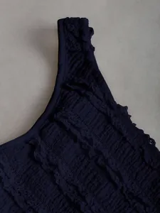 Primo piano del tessuto smocked blu navy con i delicati dettagli in pizzo fine.