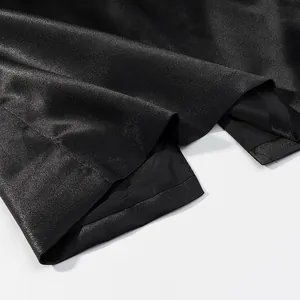 Macro view showing the glossy black satin fabric and precision hem stitching of the skirt.