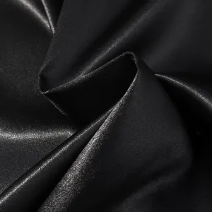 Macro shot of smooth black satin fabric with elegant silk sheen and soft texture folds