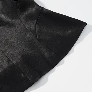Close-up detail of the smooth satin mermaid hem on a black elegant skirt suit.