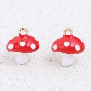 Detailed close-up of two red and white enamel mushroom charms featuring gold hanging loops