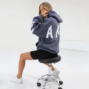 Back view of fashion oversized gray hoodie with bold white lettering on a female model.