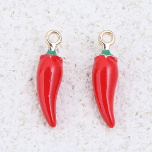 Detailed close-up of two red enamel chili pepper pendants for jewelry making