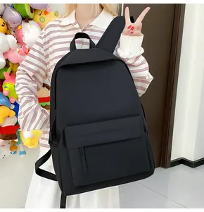 Model trägt einen einfachen schwarzen Freizeitrucksack für Schüler mit großem Volumen
