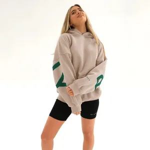 Full body view of taupe oversized hoodie with green sleeve graphics and black biker shorts
