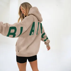 Close-up detail of beige oversized hooded sweatshirt featuring a bold green BLAKE print