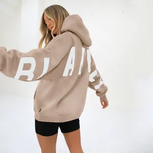 Close-up back view of an oversized beige hoodie with bold white printed lettering detail