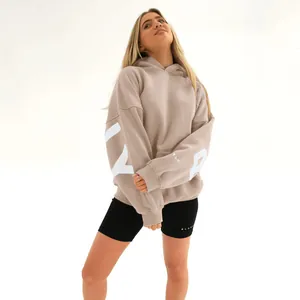 Model wearing oversized khaki hoodie with white letter print and black biker shorts.