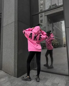 Back view of a vibrant pink oversized hoodie with bold AKE letter print