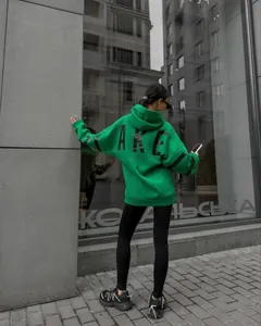 Rear view of a stylish green oversized hoodie featuring bold black BLAKE text print detail