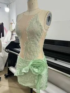Close-up detail of mint green lace evening gown featuring a large sequined flower ornament