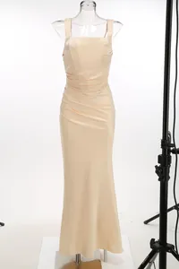 Champagne evening gown detail showing ruched pleated fabric and elegant mermaid fit.