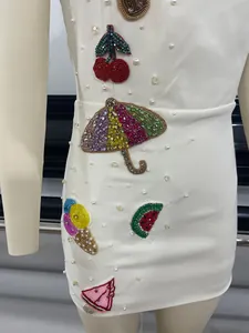 Detail shot of white mini dress featuring colorful beaded patches and scattering pearls