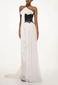 Elegant white backless halter gown featuring black lace bodice detail and a flowing train.