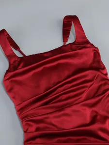 Close-up of burgundy satin dress with elegant ruching and wide straps for evening events.