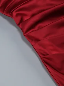 Macro detail of red pleated satin fabric on a formal evening gown with glossy finish.