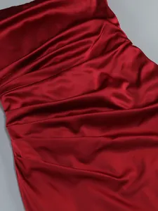 Close-up of luxurious red satin fabric with elegant ruched pleated detail for evening dress.