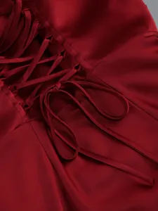 Close-up of deep red satin dress featuring elegant lace-up tie detail and silk texture