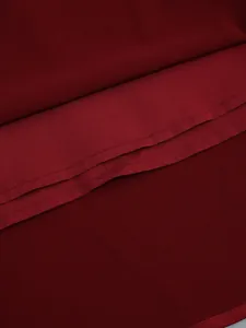 Macro detail view of burgundy dress showing fine fabric texture and neat hem stitching