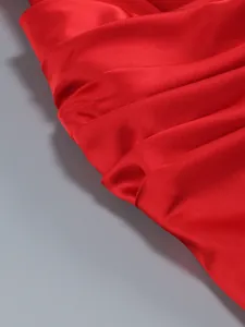 Detailed macro view of pleated red satin fabric on a elegant off-shoulder cocktail dress