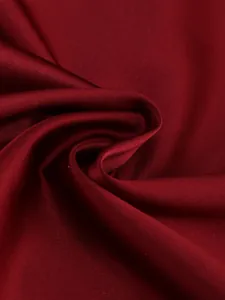 Close-up of elegant burgundy satin fabric showing luxurious silk texture and smooth drapes