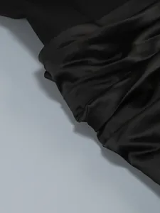 Detail shot of high-quality black satin fabric showing elegant pleats and luxury sheen