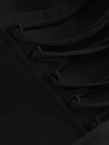 Macro view showing the intricate lace-up tie detail on a high-quality black dress