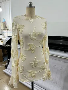 Detail view of a cream long-sleeved lace dress with ribbon floral embroidery