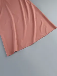 Macro view showing the fine stitching and smooth fabric texture of a dusty rose dress hem