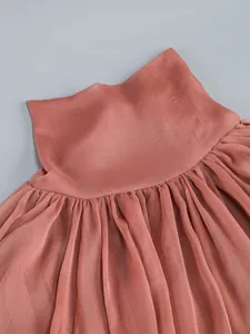 Close-up view of elegant pleated ruffles on a cinnamon pink sheer dress detail.