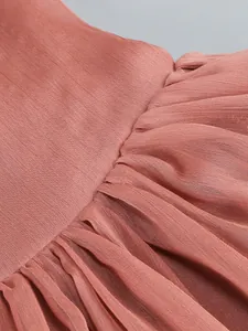 Close-up detail of pleated sheer chiffon fabric on a terracotta long-sleeved evening dress