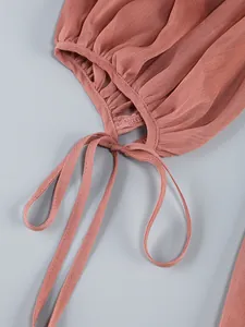 Detail view of sheer pleated dress with coral ruffle and delicate tie closure strings.