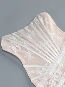 Close-up view of white floral lace and sheer mesh detailing on a corset dress