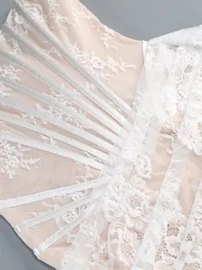 Detailed view showing the intricate white floral lace and silver boning straps on a corset dress